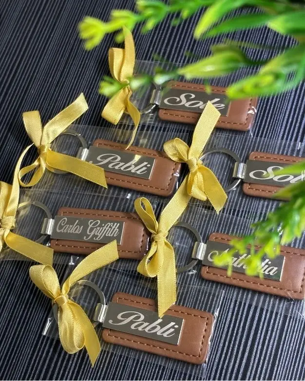 Varios llaveros de cuero personalizados con nombres, listos para regalar con moño